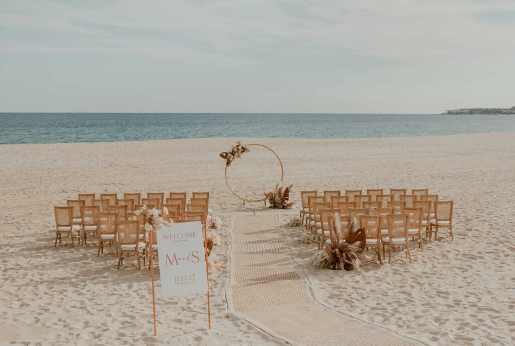 Beach wedding ceremony set up in neutral colors and pink touches. Los cabos.
