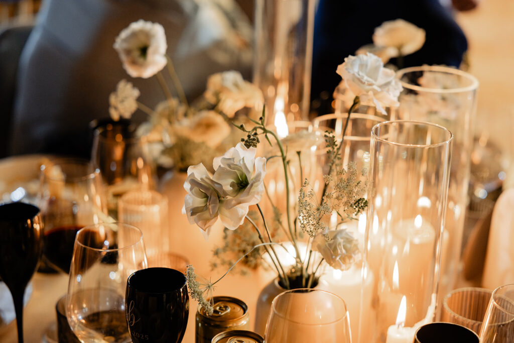 Round tables centerpiece with candles in all shaoes and sizes and touches of flowers. 