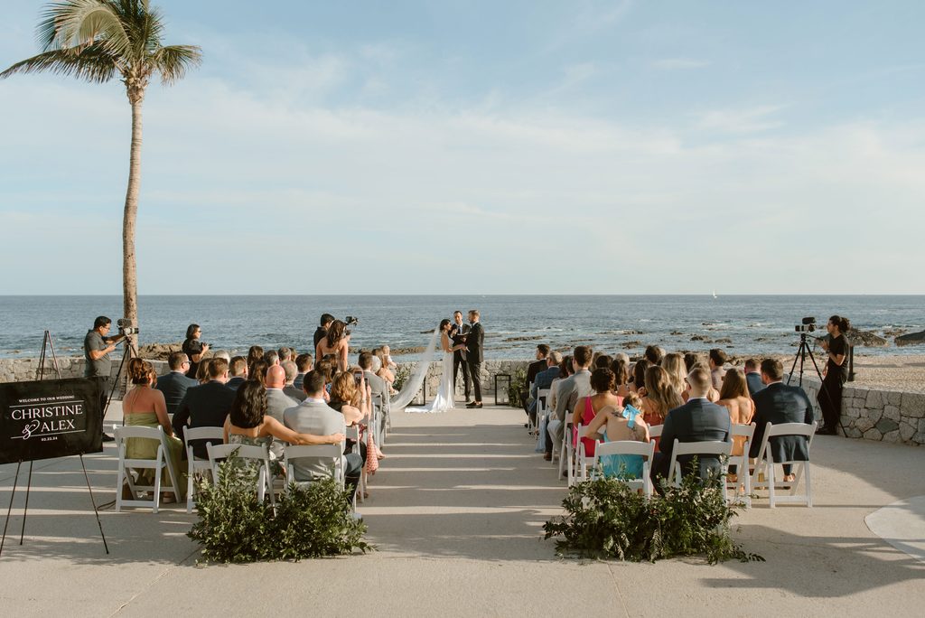 Oceanfront wedding ceremony at Fiesta Americana Los Cabos with white chairs and greenery