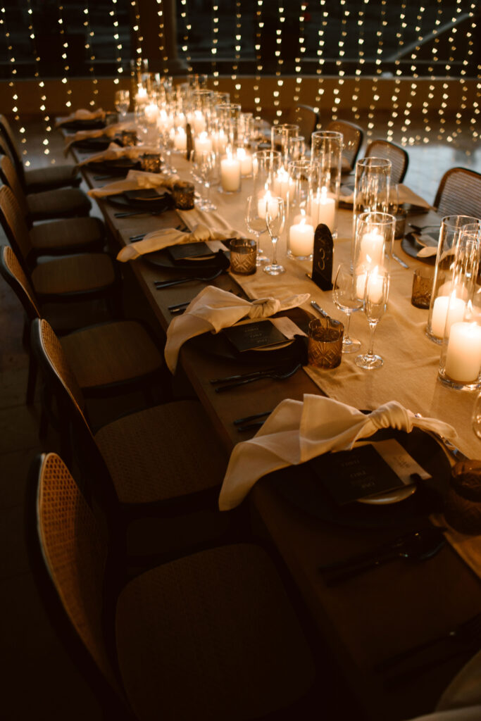 Elegant wedding reception table with black place settings, warm candlelight and minimalist decor in Los Cabos.