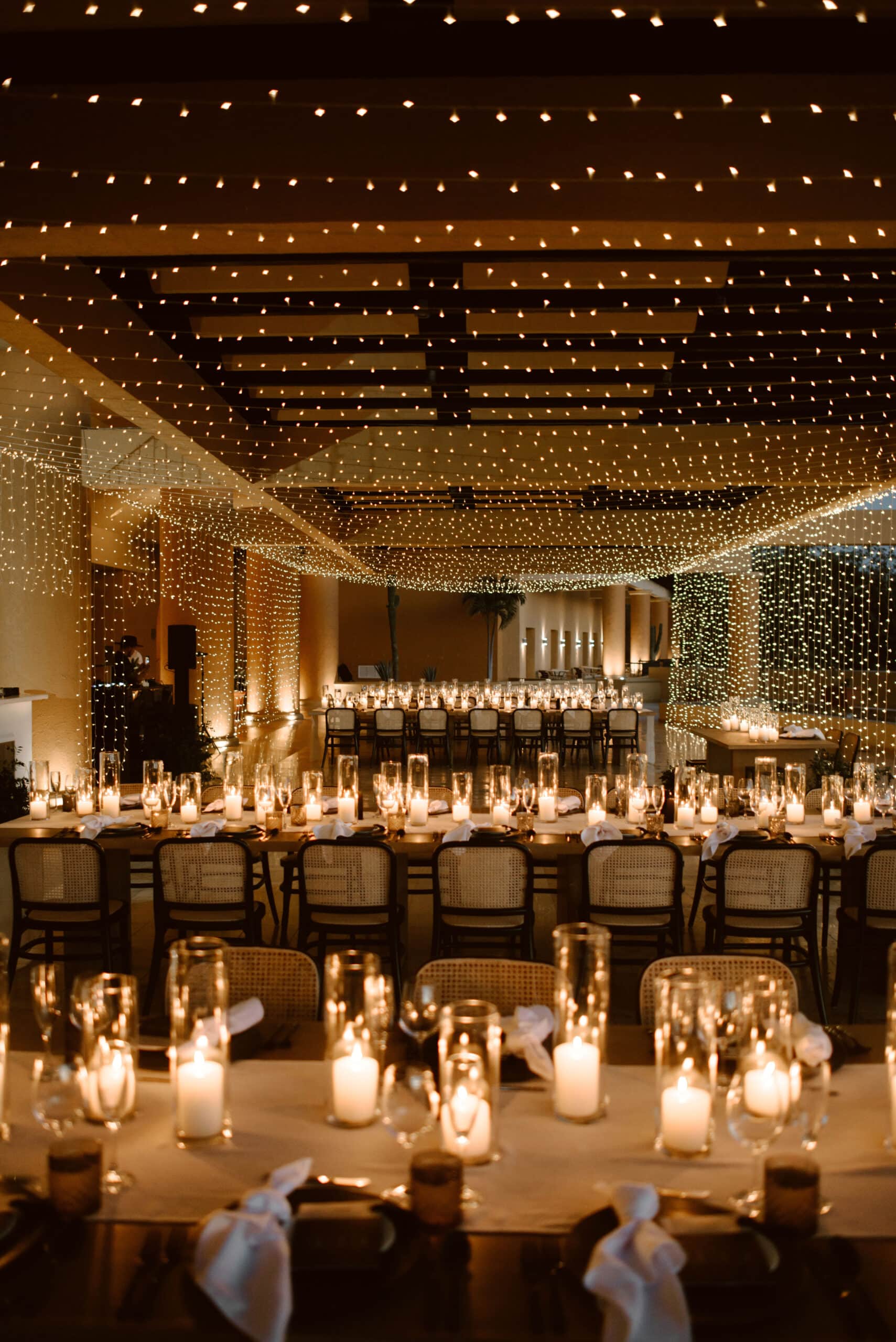 Luxury candlelit wedding reception at Fiesta Americana Los Cabos with fairy lights and long wooden tables