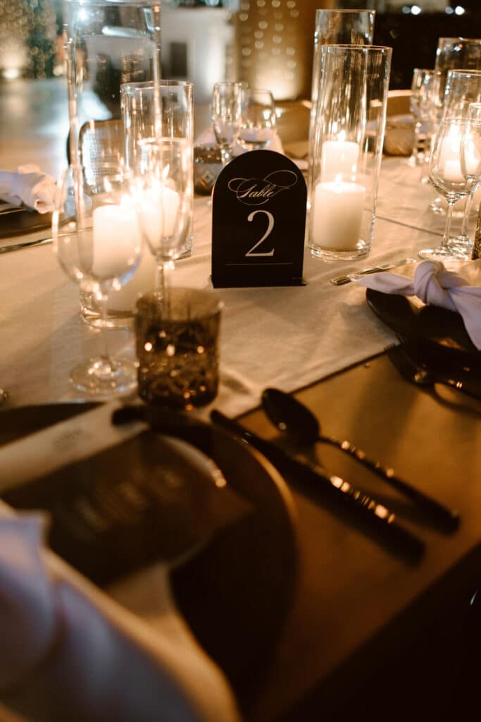 Elegant wedding reception table with black place settings, warm candlelight and minimalist decor in Los Cabos.
