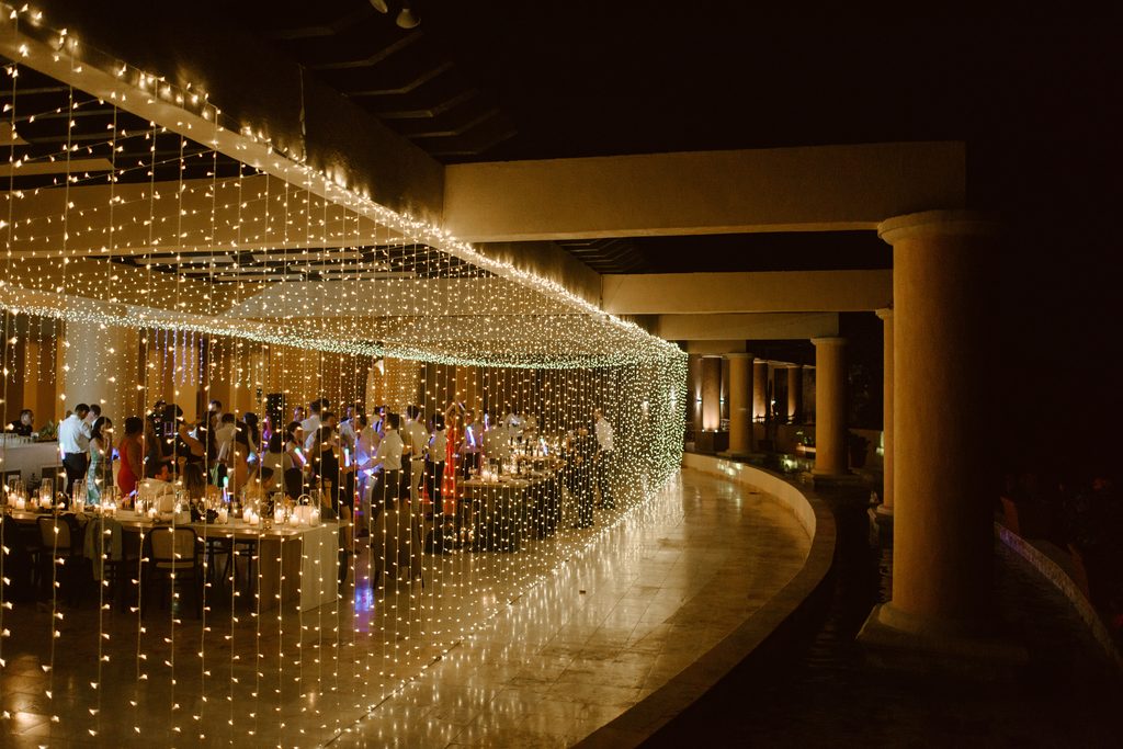 Romantic wedding reception in Cabo with hanging fairy lights and candlelit tables
