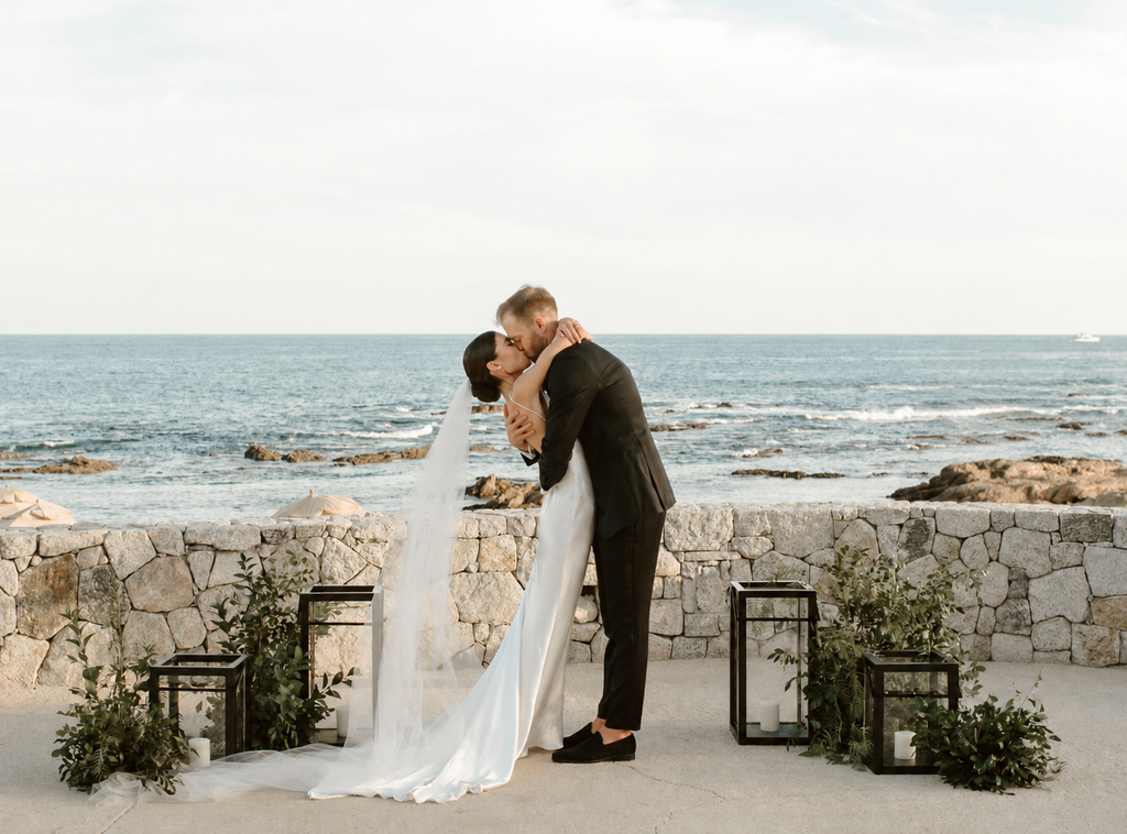 Bride and groom sharing their first kiss during an oceanfront wedding ceremony in Los Cabos